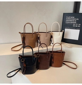 Detail of minimalist bucket bags in earth tones featuring decorative wood bead tassels
