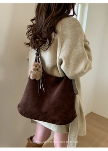 Brown suede tote bag with cute bear charm worn over a beige textured winter coat