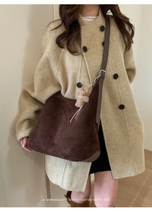 Detail of suede tote bag with plush bear charm and adjustable dark brown leather strap