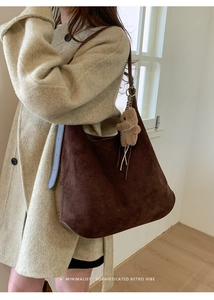 Detail of dark brown suede hobo bag with teddy bear charm and soft minimalist aesthetic
