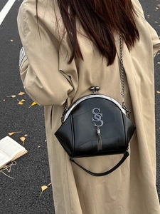 Schwarze Retro-Ledertasche mit Metall-S-Verschluss und Fransen auf herbstlicher Straße