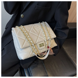 Close-up of quilted cream crossbody bag with gold chain strap and metal lock detail