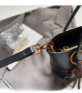 Detailed close-up of retro gold metal hardware and lobster clasp on black leather bucket bag