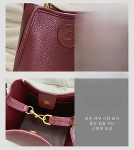 Detail of burgundy pebbled leather handbag featuring embossed logo and gold magnetic closure