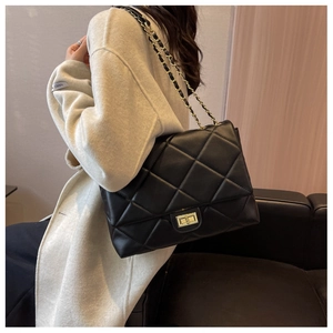 Detail view of black quilted chain bag with gold metal clasp and premium leather texture