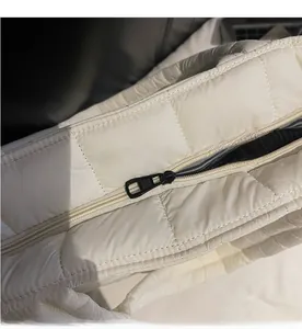 Detail of smooth black metal zipper and white quilted nylon fabric on a large puffer bag