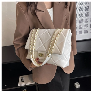 Detail of quilted beige crossbody bag with gold chain strap and turn-lock closure