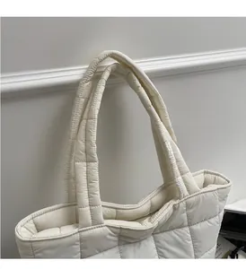 Detail of white quilted tote bag featuring padded handles and durable diamond stitching