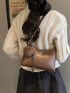 Brown matte faux leather crossbody dumpling bag with plush charm on a female model