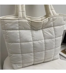 Detailed macro view of quilted cream tote bag with large square stitching and soft texture