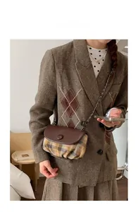 Detailed model shot of vintage plaid saddle bag with brown faux leather flap and chain strap