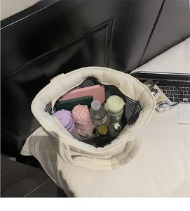 Spacious interior of white quilted tote bag holding a tablet, umbrella, and water bottle