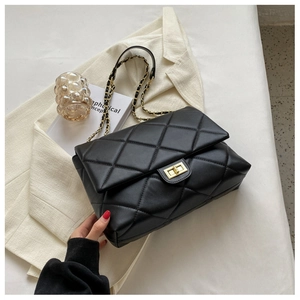 Detail of black quilted leather shoulder bag with gold metal twist lock and chain strap