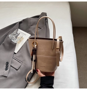 Detail of beige bucket bag with tassel pendant and FASHION & BAGS PARIS logo