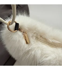 Close-up of smooth gold zipper and plush white faux fur texture on the luxury bag