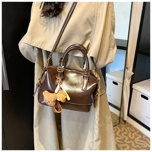 Detail of glossy dark brown oil wax leather Boston bag with plush bear charm accessory