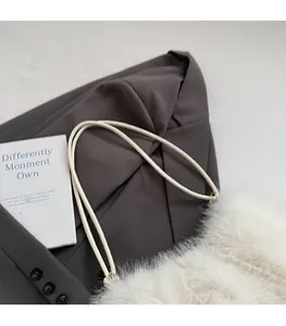 Detail of plush white faux fur shoulder bag with slender straps on gray background