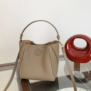Detailed close-up of taupe pebbled leather bucket bag with gold hardware and top handle