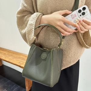 Close-up of dark green litchi grain leather bucket bag with metallic buckle strap