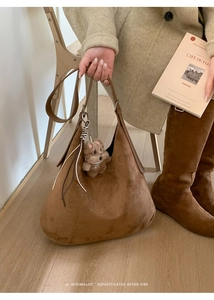 Detail of a large brown suede Hobo bag featuring a cute plush bear pendant accessory
