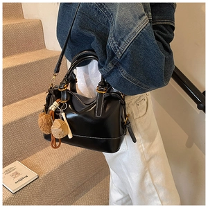 Detail of black leather Boston bag featuring white contrast stitching and gold metal hardware