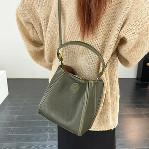 Detail of dark green lychee pattern leather bucket bag with top handle and logo