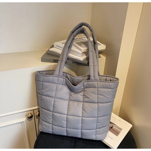 Close-up of gray quilted tote bag featuring padded puffer texture and square stitching