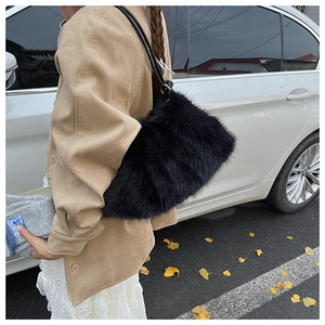 Street style shot of a black faux fur shoulder bag paired with an elegant beige coat
