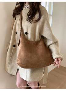Detail of large brown faux suede hobo bag with a retro minimalist vibe and leather strap