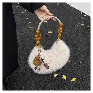 Detail of cream fuzzy bag with wooden bead handle and brown plush monster charm decor