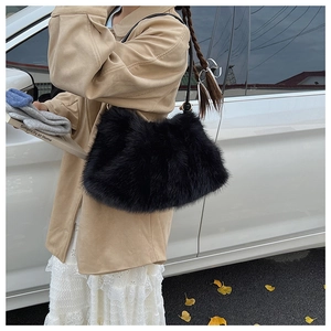 Detail of a fluffy black faux fur shoulder bag worn in an autumn street style setting