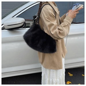 Detail of a fluffy black faux fur shoulder bag with leather strap in a street setting