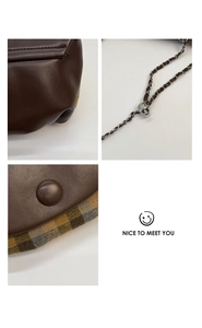 Detail of brown leather saddle bag featuring vintage plaid fabric and adjustable chain strap