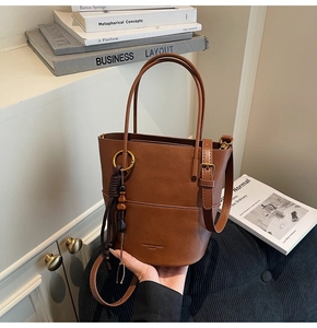 Detailed macro view of brown leather bucket bag with fringe charm and fashion logo