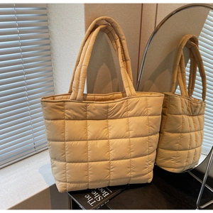 Close-up of beige quilted puffer tote bag with classic large square stitching and soft texture