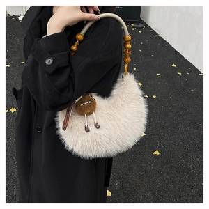 Detail of plush faux fur hobo bag with wooden bead handle and cute charm on black coat