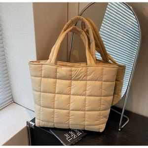 Detail of light beige quilted tote bag showing large plaid pattern and soft texture