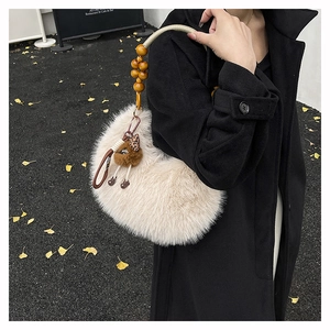Detail view of fuzzy beige faux fur handbag with wooden bead handle and brown plush charm
