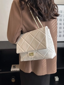 Quilted white shoulder bag with gold chain strap and turn-lock closure on model