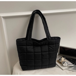Detail of black quilted puffer tote bag with spacious interior for work and travel