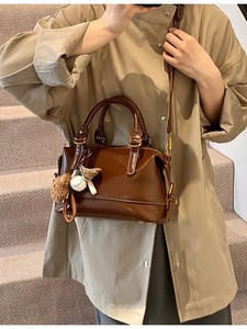 Retro dark brown Boston bag with shoulder strap and plush charm shown on stairs