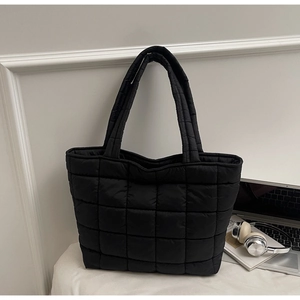 Detail view of large black quilted tote bag with padded grid pattern and shoulder straps