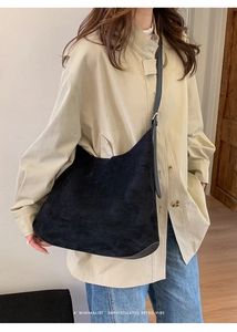 Minimalist black suede hobo bag with adjustable leather strap worn by a model