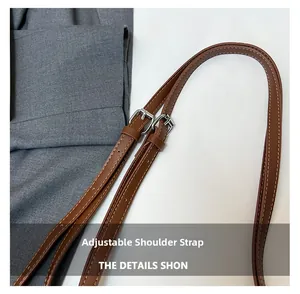 Close-up of brown leather adjustable shoulder strap with silver buckles and stitching