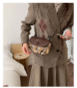 Detail of vintage saddle bag with brown check fabric and elegant leather flap