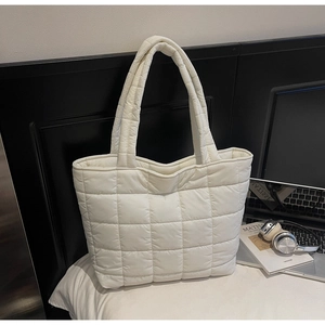 Detail shot of the white puffer tote bag showing quilted nylon texture and sturdy handles