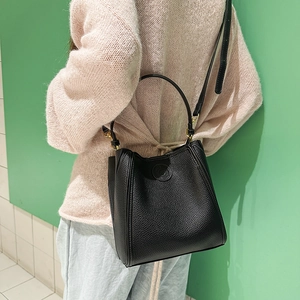 Close-up of black litchi pattern bucket bag with gold hardware and shoulder strap