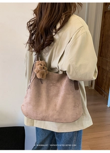 Brown frosted suede tote bag with cute plush bear charm in a cozy minimalist interior