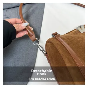 Close-up of brown suede tote bag with detachable silver hook and metallic V detail