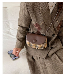 Detail of retro plaid saddle bag with brown leather flap and silver chain strap